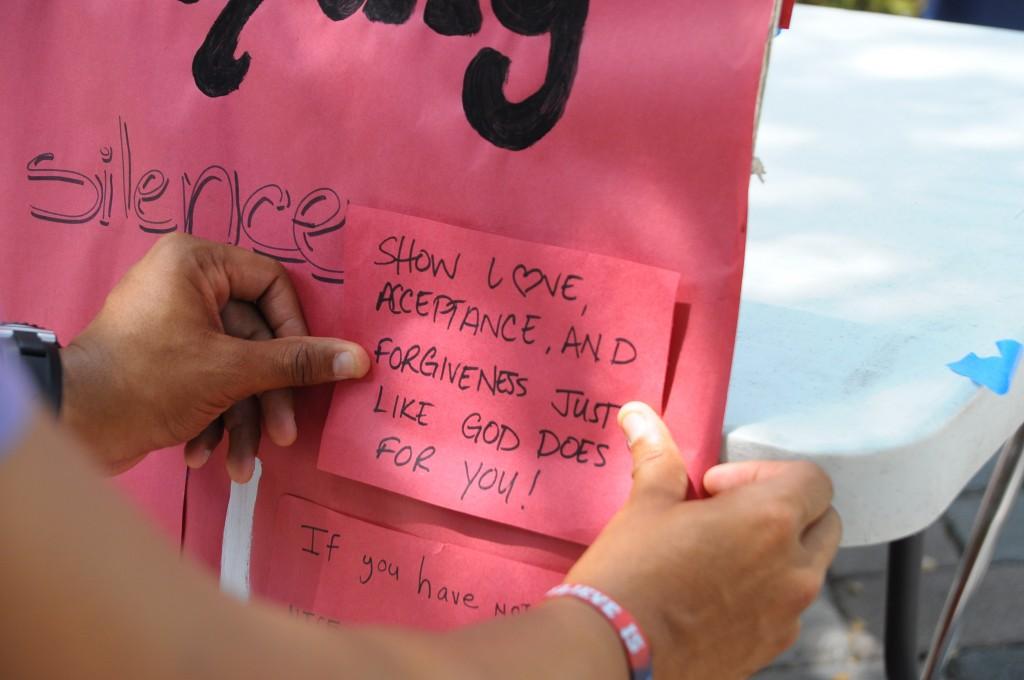Vince Long, a biomedical science master's student, posts a message on the "Speak out against bullying" board at the Day of Silence event on Friday, April 19. Photo by Michelle Friswell.