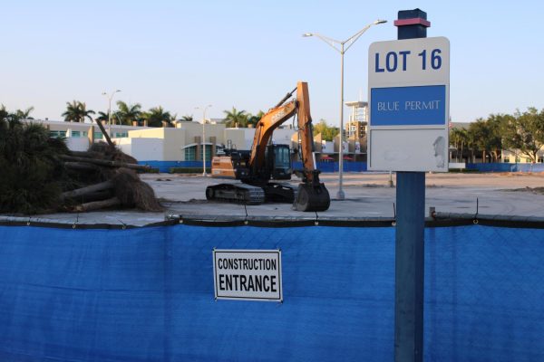Parking lot 16, reserved for commuting students with blue permits, had an excavator and landscaping debris at the construction site surrounded by temporary blue privacy screen fencing on May 17.