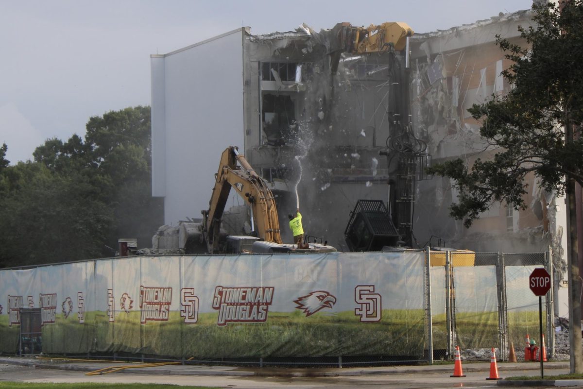 A large excavator began tearing down the 1200 building at Marjory Stoneman Douglas High School on June 15, causing debris to fall and dust to spread across the campus.