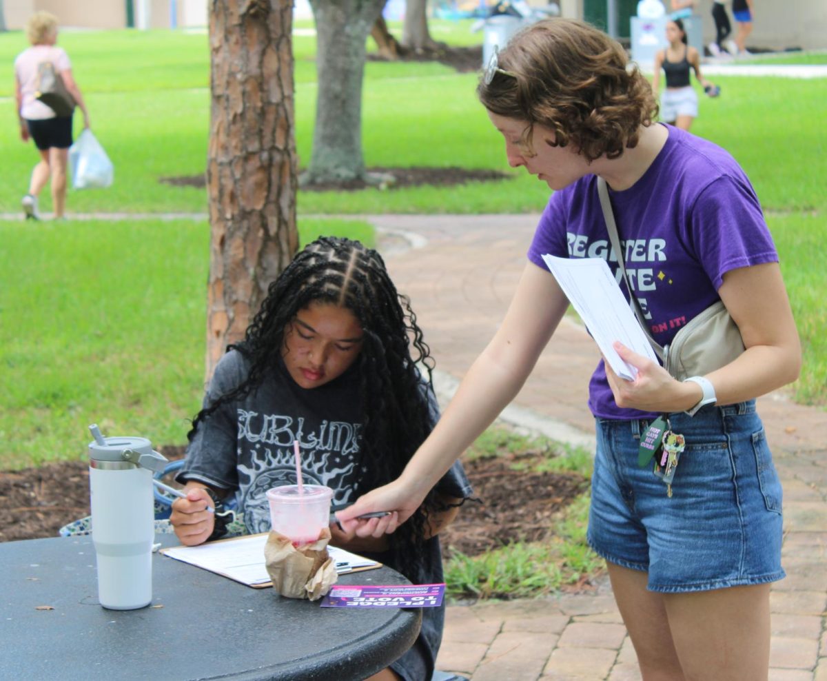 Allison Minnerly assisting Shaila Padilla in signing the voting registration form.