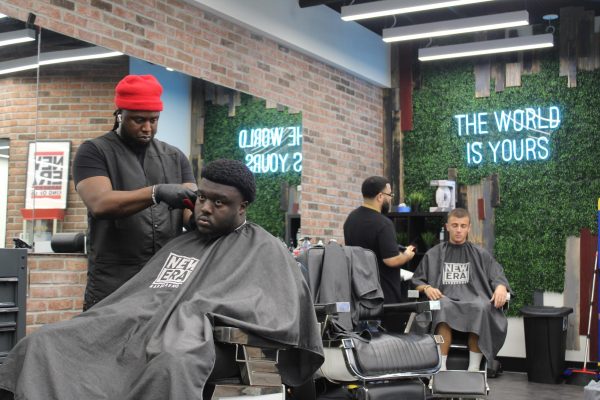 A picture of Noel, one of the New Era Barbershop's resident barbers, cutting a client's hair. 