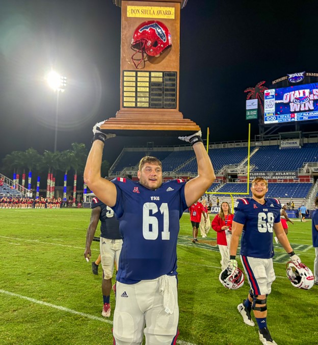 Offensive Lineman #61, Michael Unis hold the Don Shula Trophy over his head brining it back to the locker room at the Howard Schnellenberger Field  on September 14, 2024. 