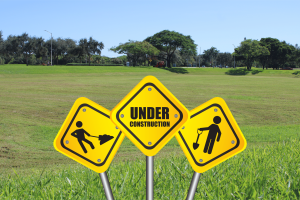 Photo of the empty field where new dorms are set to be constructed, featuring a Canva-designed construction sign.