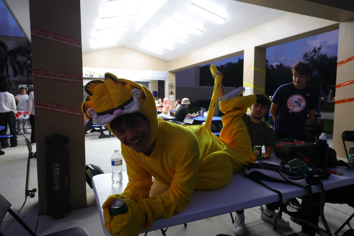 A student in a Garfield costume posing on a table at LHA's "El Apagon" event.