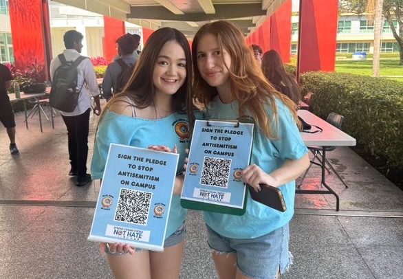 Ariela Fischer and Eden Hebron, Hillel volunteers, holding up QR codes for students to sign the antisemitism campaign.
