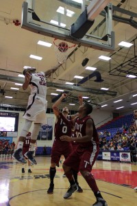 Jordan McCoy skies to tip in a basket. The senior forward totaled eight points and seven rebounds against the Trojans. Photo by Melissa Landolfa.