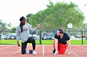 Aromashodu shows UP Reporter Zack Kelberman the proper way to line up on the “blocks” for a sprint. She joked that I had trouble getting in the correct stance. Photo by Ryan Murphy